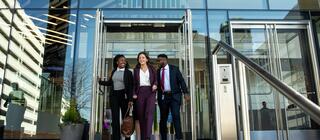 three graduate students walking out of building