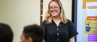 smiling teacher at the front of the classroom