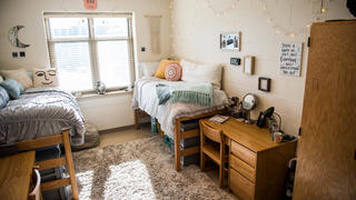 A dorm room with two beds and light coming through the window