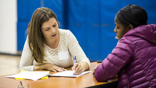A student teacher instructs an elementary student