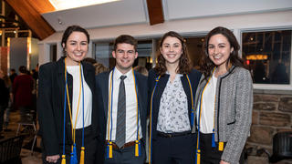 A group of honors students stands together smiling at the camera