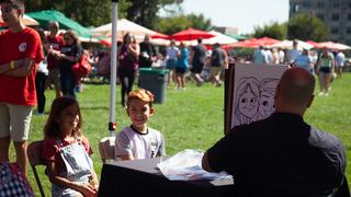 2 children sitting getting a caricature