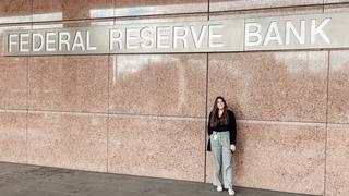 Alumna Marissa Abel standing in front of the Federal Reserve Bank sign
