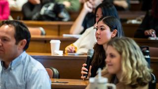 Female student seated holds microphone