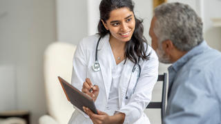 A young female doctor sits with a senior patient.