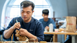 Chen Zongwei carefully works on a wooden statue of Nezha the Third Prince.