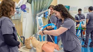 Respiratory care students holding equipment while working on a manniquin in Saint Joseph's Simulation Center