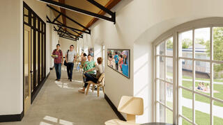 A long hallway filled with people walking and some sitting at a table