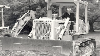 1987: Nicholas S. Rashford, S.J., on a Caterpillar bulldozer at the McShain Hall groundbreaking.