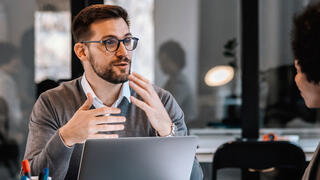 Business student talking over laptop to colleague