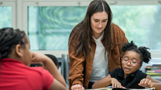 Teacher looking over shoulder of a student
