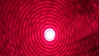 A red light pattern with a solid glowing circle of light in the center. It is surrounded by thinner, uniform rings that gradually lose their intensity going outwards. 