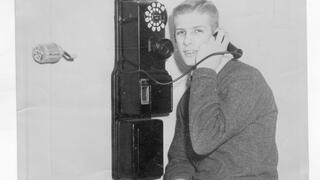 student on a old-time pay phone 1958