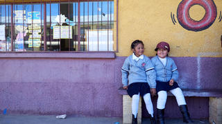 two girls sitting in front of a school