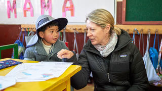 a young boy talking to a woman in a classroom