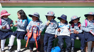 a group of 7 young boys and girls in front of a school