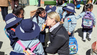 a woman crouched down to talk to young school children