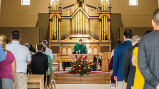 A green frocked priest stands in front of his congregation during Catholic mass services held at the Chapel of Saint Joseph,