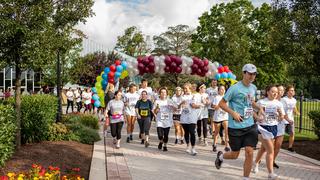Runners under a balloon arch at the Kinney 5K