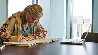 A student with headphones on studies at a table