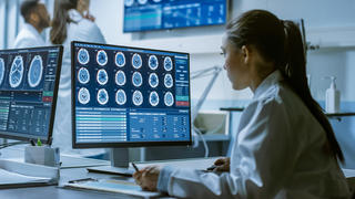 a neuroscientist looking at scans of the brain inside a lab
