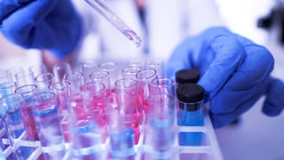 a scientist injecting chemicals into test tubes