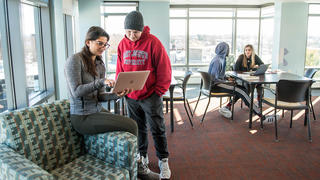 two students inside villiger hall, looking at a laptop