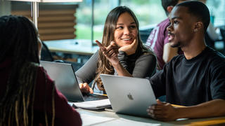 two college students talking to each other in a library at Saint Joseph's University