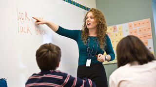 teacher pointing at a whiteboard in a classroom