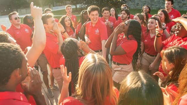 Orientation leaders in red shirts standing in a circle shouting