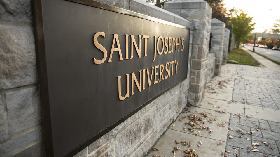 A large black metal plaque emblazoned with the words Saint Joseph's University