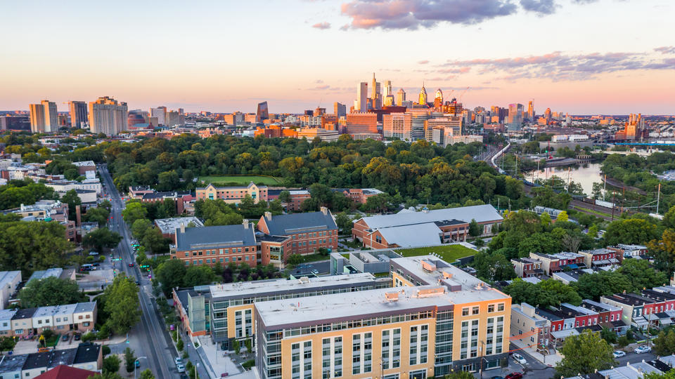 Saint Joseph's University City green campus is populated by large brick academic buildings and modern student dormitories, the skyscrapers of Center City can be seen in the distance