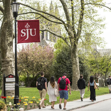 campus path on a bright day with students walking. A red school banner hangs over the path.