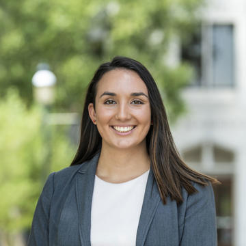 Kayla Cecchine smiles at camera standing in front of Mandeville Hall