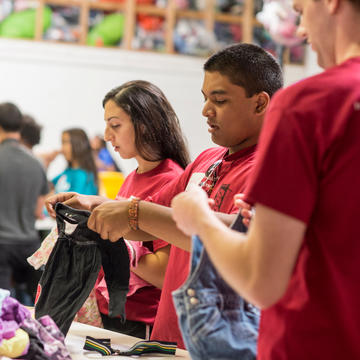 Saint Joseph's students fold clothing as part of a clothing drive at a local high school