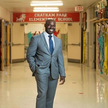 jabari whitehead, ed.d., wearing a suit and standing inside an elementary school hallway