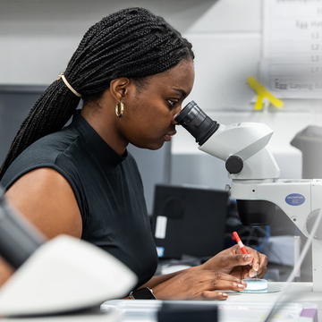 2021 McNulty Summer Scholar student in the lab in front of a microscope.