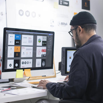 Man sitting behind computer creating logos on computer software