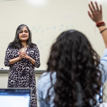 Usha Rao, PhD, teaching in a classroom in Barbelin Hall with a female student's hand raised