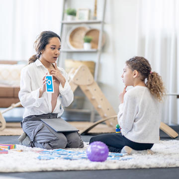 Speech pathologist helping child with her speech