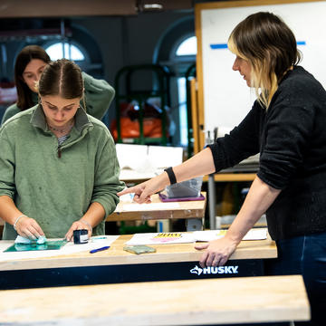 SJU art education professor helping student in art lab