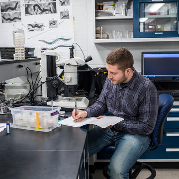 sju biology student taking notes in lab