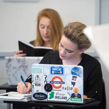 Saint Joseph University students writing and researching on laptop