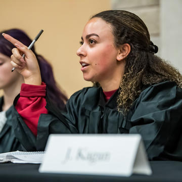 Saint Joseph's University student in moot court sitting behind table pointing at speaker