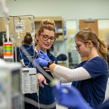 Two female nurses putting together an IV pole