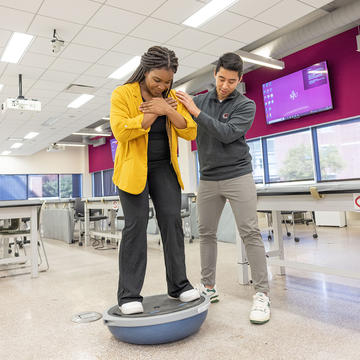 Physical Therapy Students working on an exercise on a ball to maximize core strength and balance.