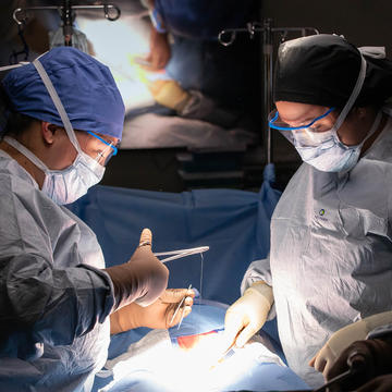 Two nurses stitching up a patient in operation room 