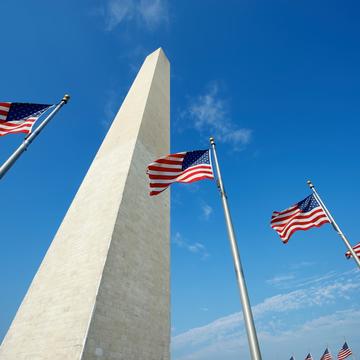 Washington Monument with three American flags hanging in front of it