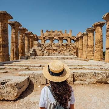 Woman wearing a hat while standing in front of ancient ruins in a desert