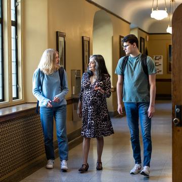 Two students walking down a hallway with a faculty member